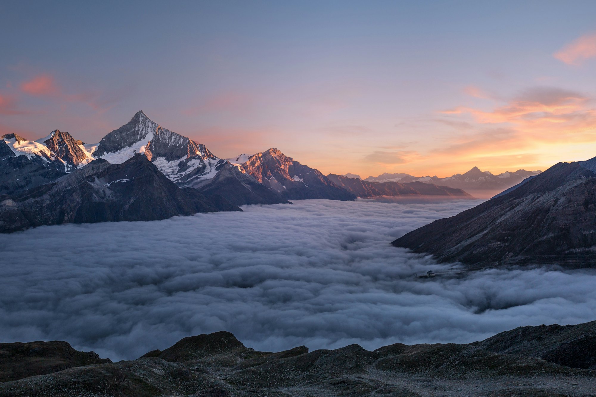 A fjord at dusk beneath snow-covered peaks
