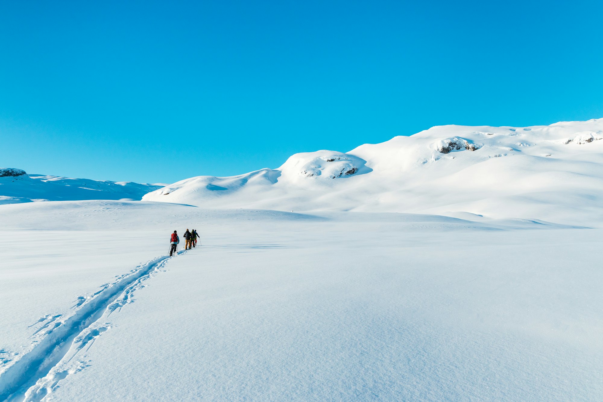Two ski tourers crossing a snow-covered field beneath the peaks of northern Norway